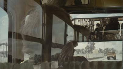 A painting showing multiple reflections of passengers inside a bus, creating a layered and abstract visual effect. The scene includes a view through bus windows of a road with a yellow vehicle and trees.