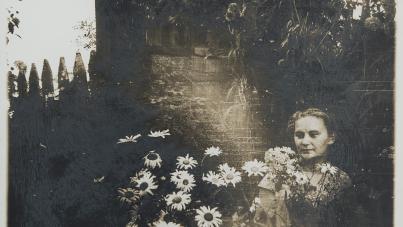A person holding flowers in front of a fence wall
