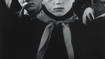 Black and white photograph showing a group of children dressed in uniforms with neckerchiefs, likely part of a youth organization or school group. Faces are partially obscured, focusing attention on clothing details and group arrangement.