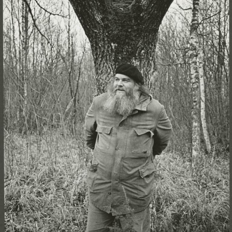 Artist Raul Meel standing in front of a tree with his arms behind his back. 