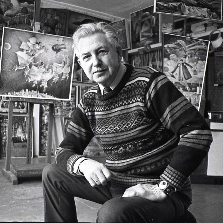 grey-haired man in the middle of his studio filled with paintings