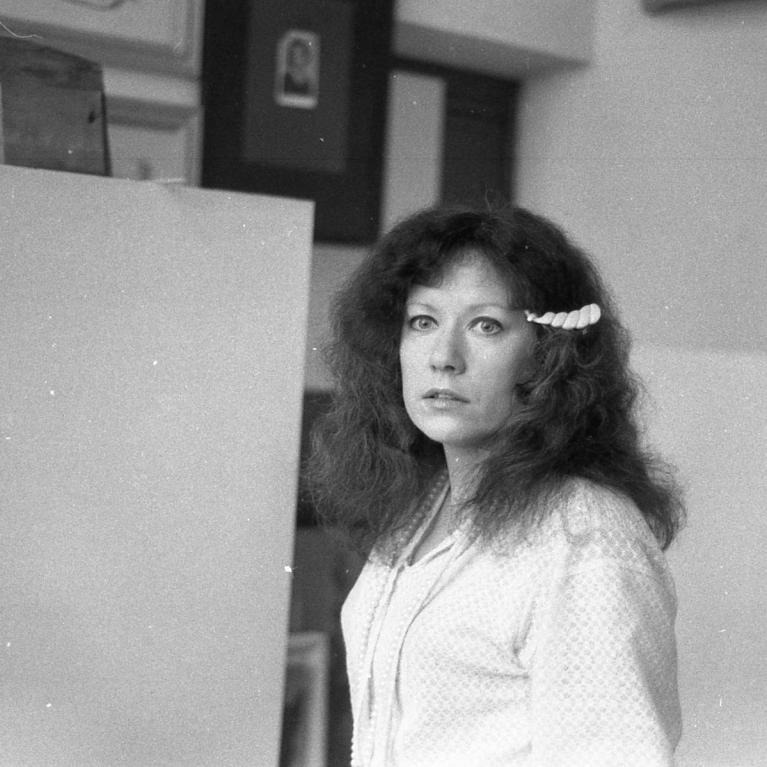 young woman with long airy wavy voluminous hair standing in the middle of a studio space surrounded by large blank canvases