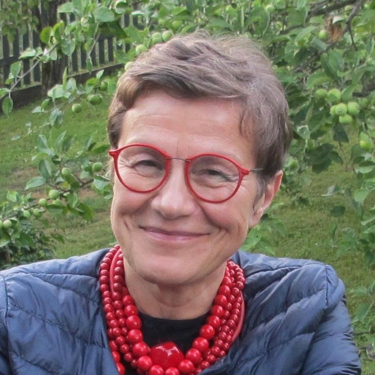 smiling older woman with short hair in glasses wearing bead necklace