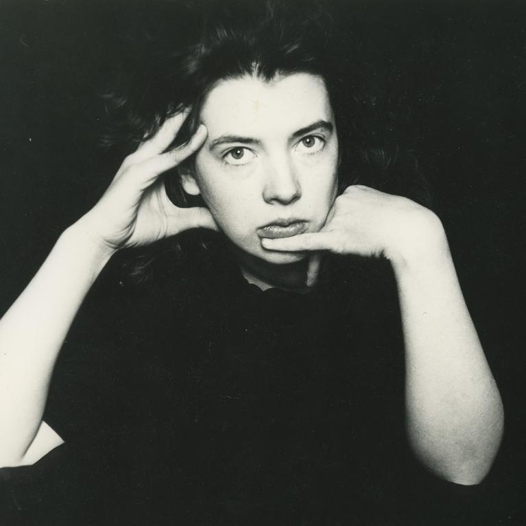 young woman resting her head on her arms, bent elbows resting on the table