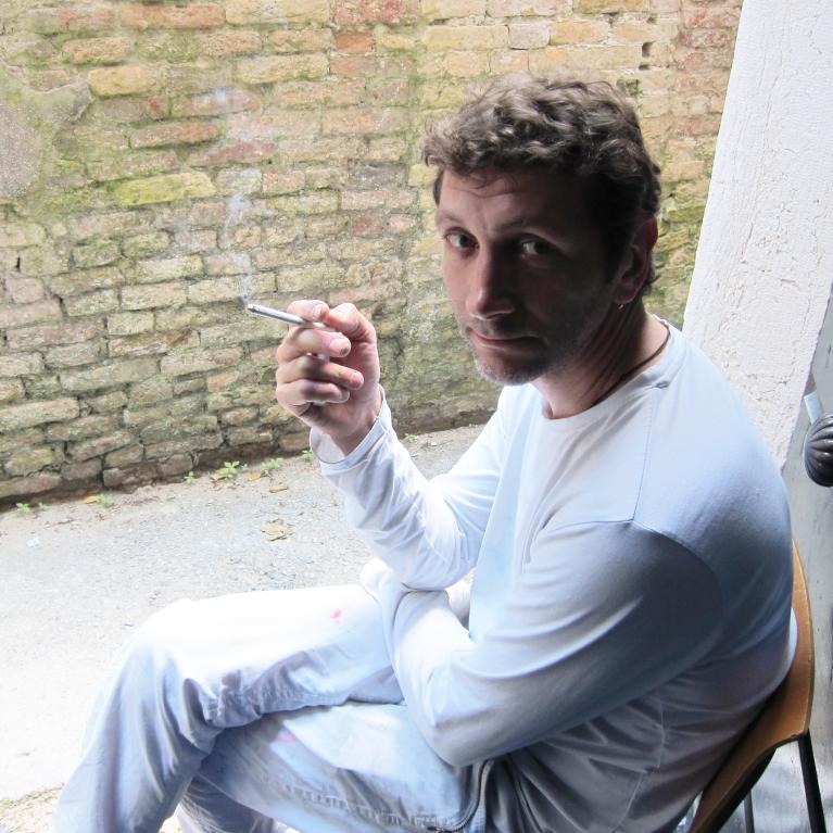 young man sitting by the door and smoking a cigarette