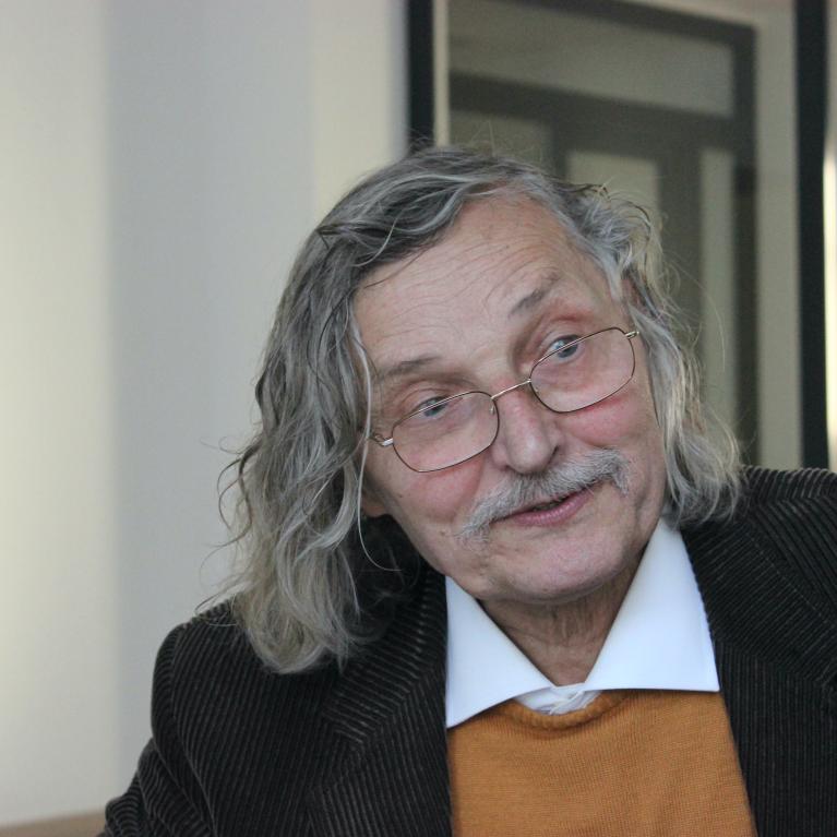 old man with long grey hair wearing glasses