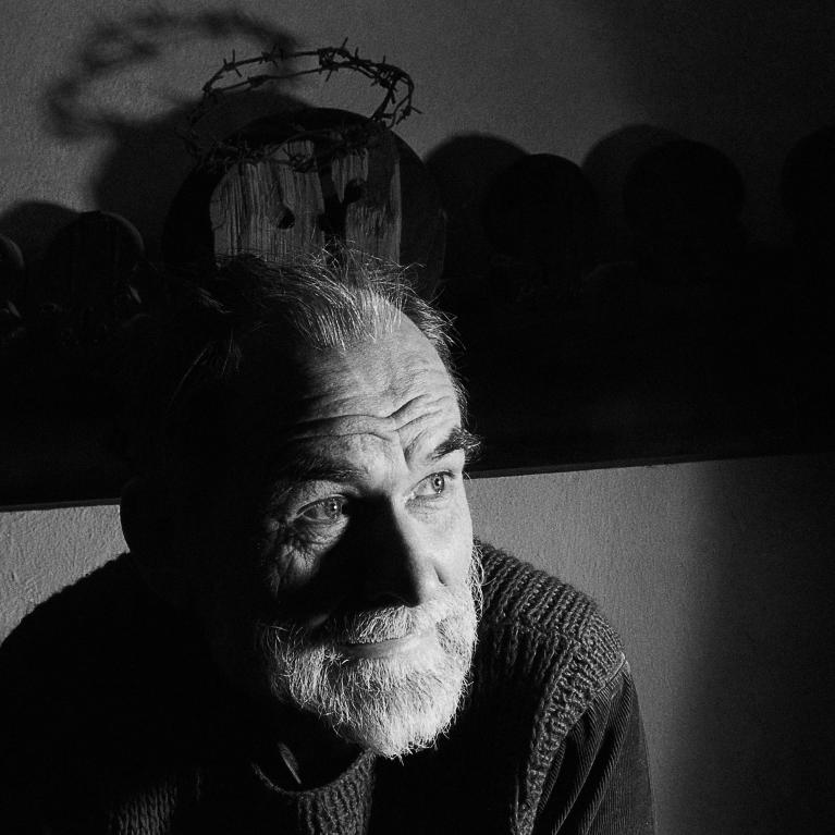 old man with beard sitting in half-dark room