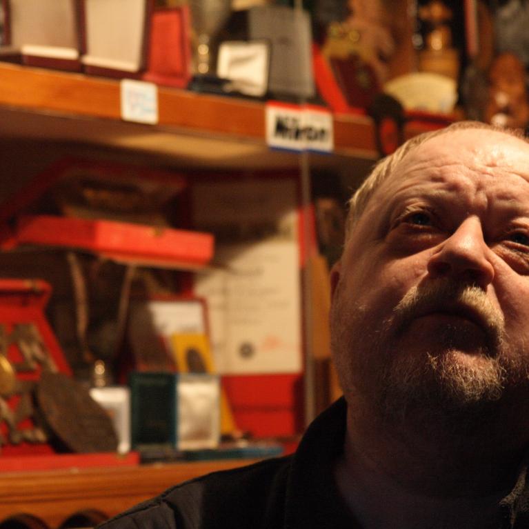older man sitting in his studio looking up