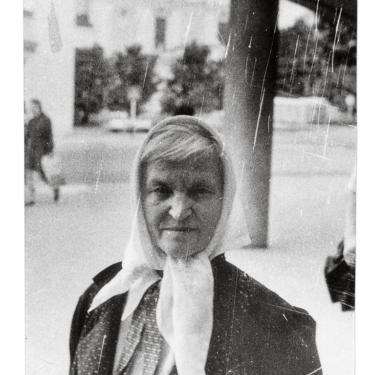 an older woman standing in the street wearing a headscarf