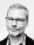a headshot of a middle-aged white man in glasses