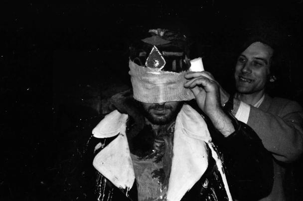 one person covering other person's eyes with gauze rolled out from a medical kit